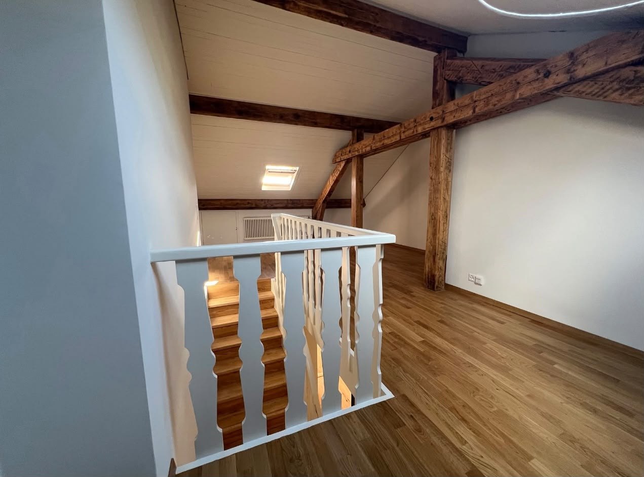 Pièce rénovée avec parquet, garde-corps et poutres apparentes