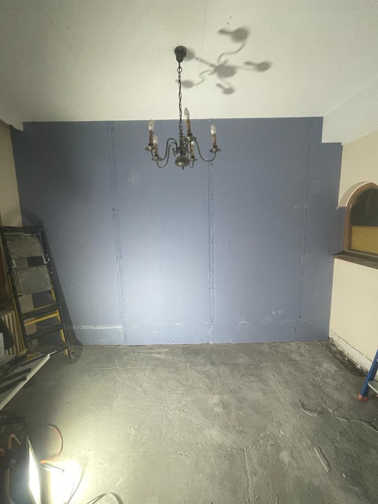 Mur recouvert de plaques de plâtre dans une pièce avec lustre